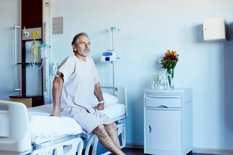 深思熟虑的成熟男人坐在医院病房的床上看向别处